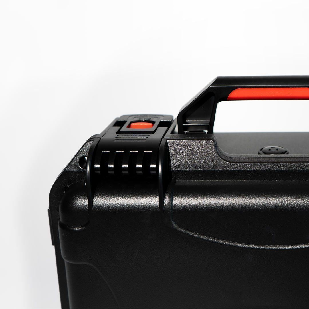 Close-up of a black suitcase handle with red accents on a white background