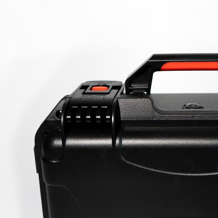 Close-up of a black suitcase handle with red accents on a white background